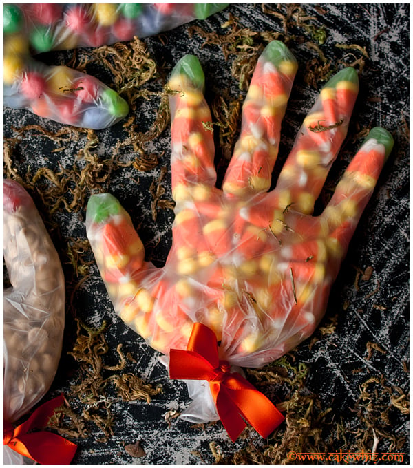Halloween Party Bags Using Plastic Gloves and Filled With Candy Corns on Rustic Black Background