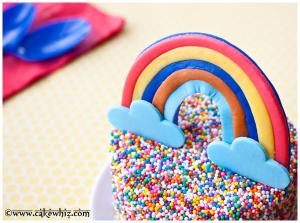 Closeup Shot of Fondant Rainbow Topper on Sprinkle Cake