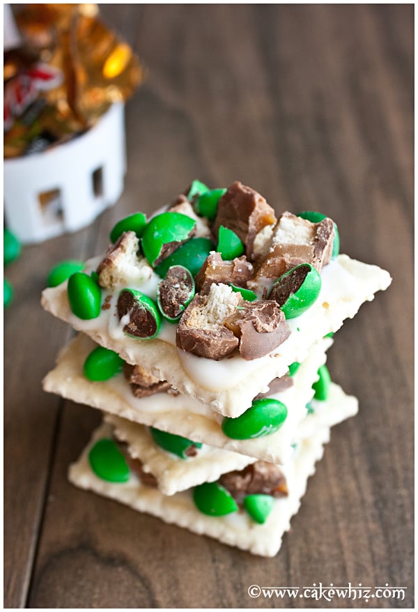 Stack of Homemade Chocolate Crackers with White Chocolate and Green Candies on Brown Wood Background
