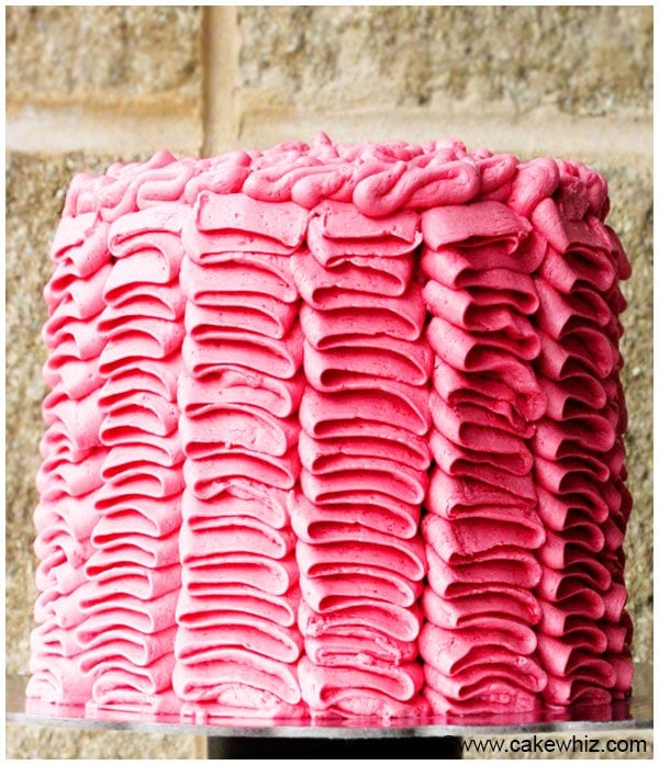 Decorated Pink Cake on Cake Stand with Brick Background