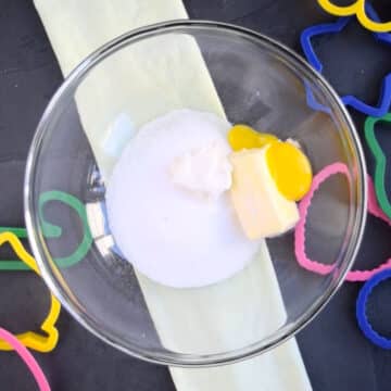 Butter, sugar, egg yolk, sour cream, vanilla in glass bowl. 
