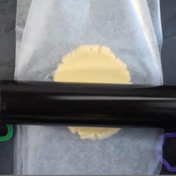 Dough being rolled out between two sheets of wax paper or parchment paper. 