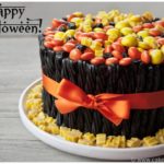 Easy Halloween Cake Decorated With Candies and Black Twizzlers on White Dish.