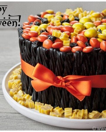 Easy Halloween Cake Decorated With Candies and Black Twizzlers on White Dish.