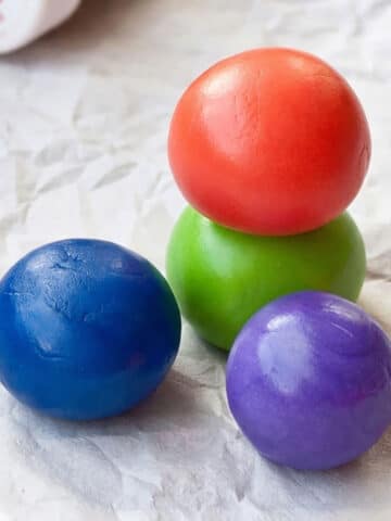 Stack of Fondant Balls And Bottles of Gel Colors to Show How to Color Fondant.