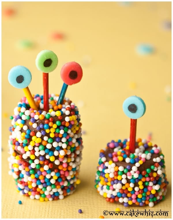 Big and Small Rolo Chocolate Monsters Covered in Sprinkles on Yellow Background. 