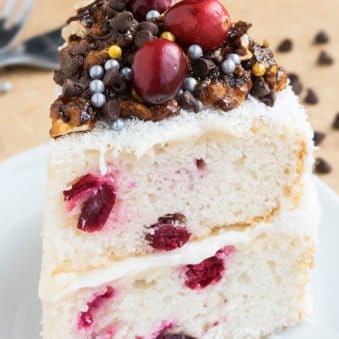 Slice of Christmas Cranberry Cake With Coconut and Cream Cheese Frosting on White Dish.