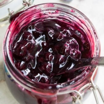 Easy Blueberry Pie Filling in Glass Jar on White Marble Background.