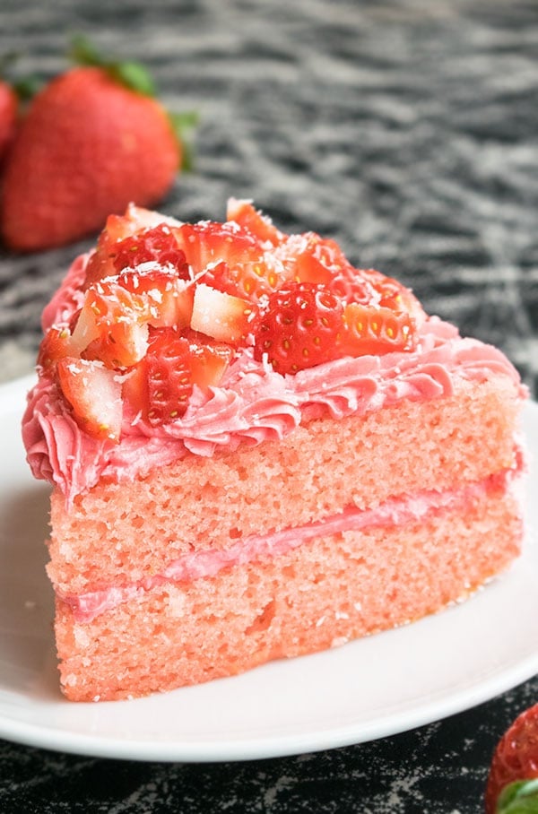 Slice of Pink Cake With Fresh Strawberry Frosting on White Dish