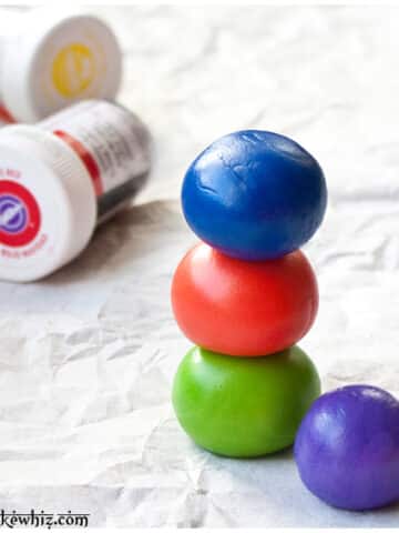 Stack of Fondant Balls And Bottles of Gel Colors to Show How to Color Fondant.