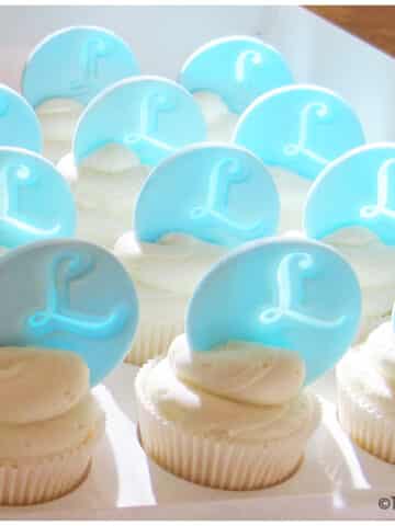 White Frosted Cupcakes With Fondant Monogram Toppers in Box.