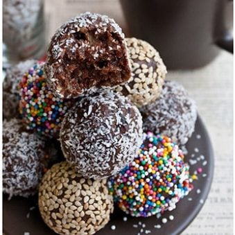 Stack of Easy Chocolate Date Balls With Various Toppings on Brown Dish.