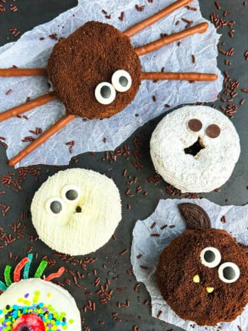 Easy Halloween Donuts (Mummy, Spider, Bat, Cat, Ghost, Monster) on Metallic Gray Background With Chocolate Sprinkles.