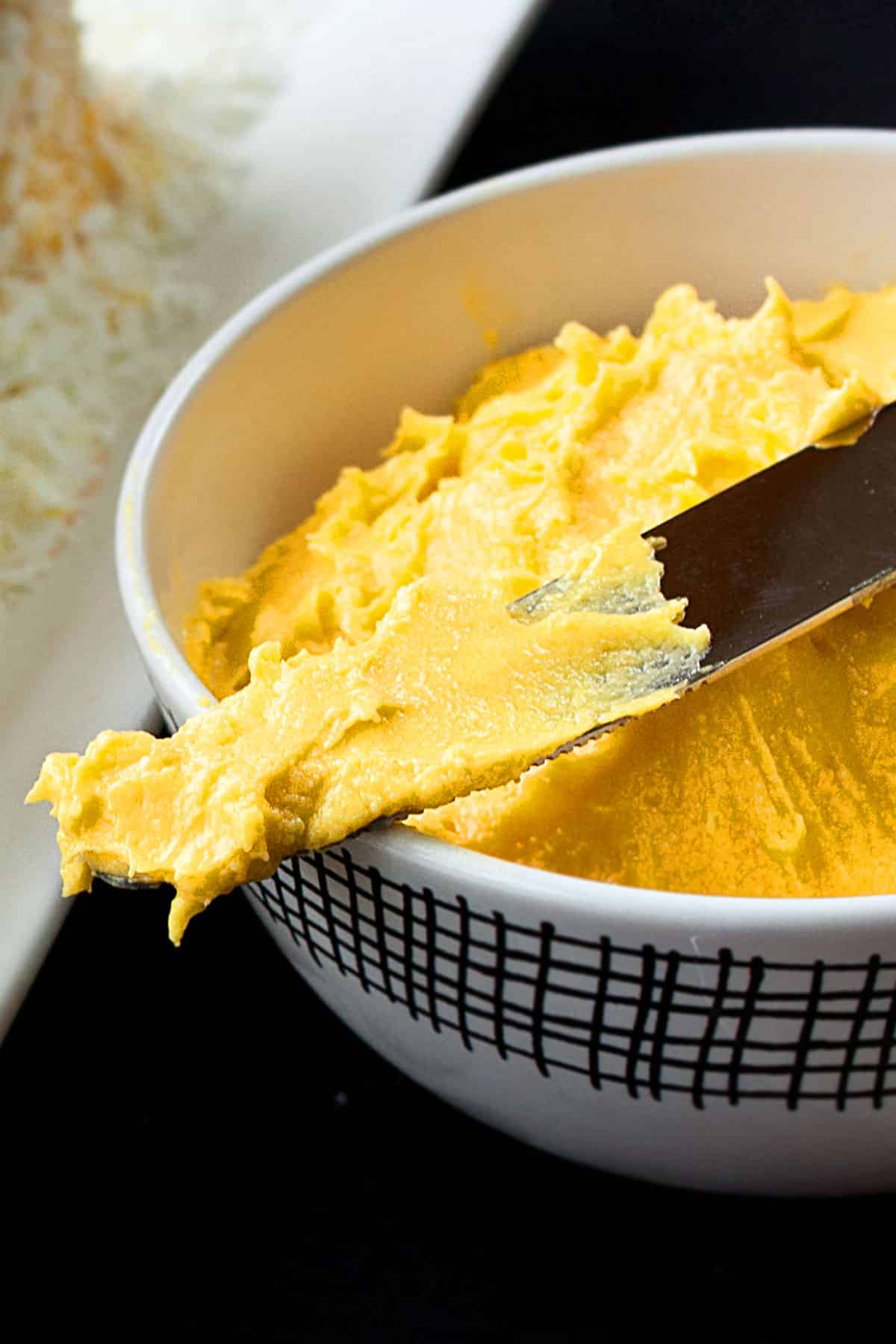 Closeup shot of yellow icing on spatula.  