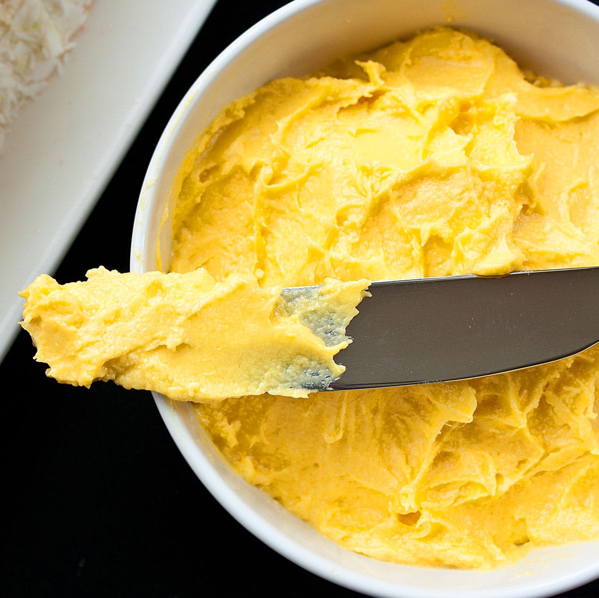 Easy Mango Frosting in White Bowl With Spatula. 
