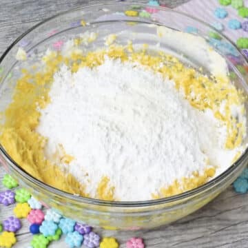 Powdered sugar added to mango mixture in glass bowl. 