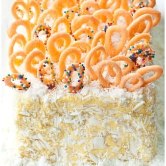 Easy Mango Cake With Mango Frosting on White Dish With Chocolate Loop Decorations.