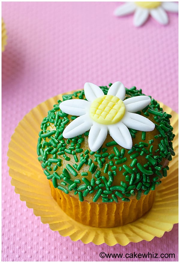 Easy Fondant Daisy Cupcakes in Yellow Cupcake Liners With Pink Background