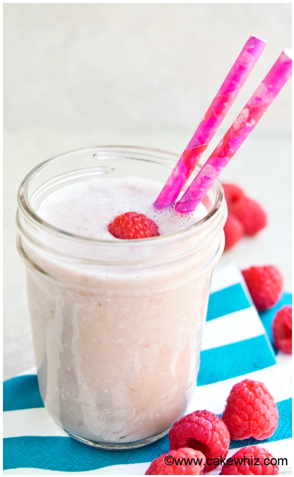 Easy Raspberry Smoothie in Glass Cup with Pink Straw on Striped Blue Napkin