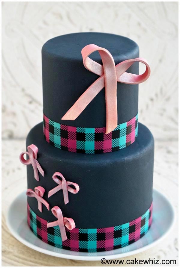 Tiered Gray Cake Decorated With Pink Fondant Bows, Placed on a White Plate