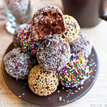Stack of Easy Chocolate Date Balls With Various Toppings on Brown Dish.
