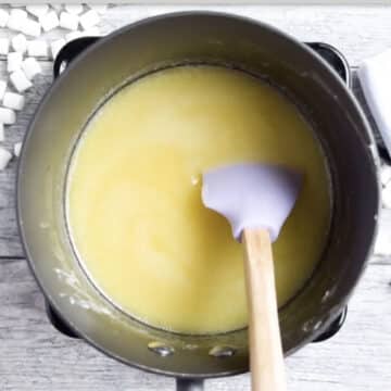 Melted butter and white chocolate with spatula in nonstick saucepan. 