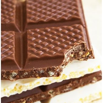 Stack of Easy Chocolate Crunch Bars With One Partially Eaten on Light Brown Background.