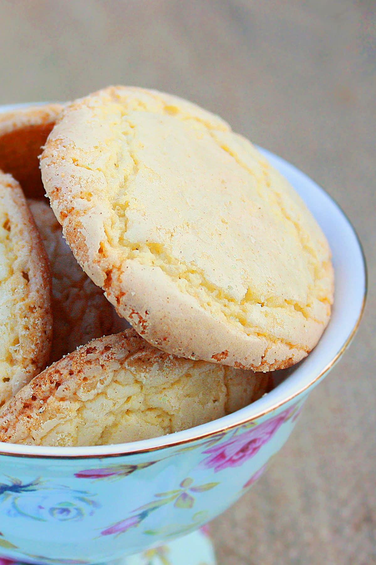 Crunchy and crispy sugar crinkle cookies in white bowl with floral design. 