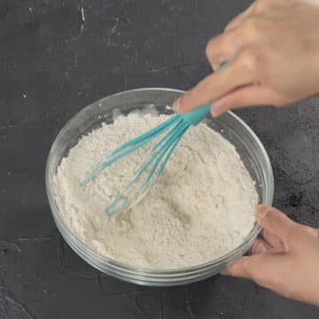 Dry ingredients being whisked together in glass bowl. 