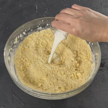 Milk being added to crumbly cookie dough. 