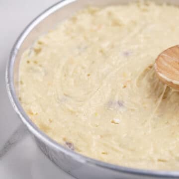 Cake batter being spread evenly with a wooden spoon.