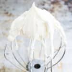 Best Easy White Stable Cream Cheese Frosting on Whisk Placed on Rustic Metal Tray.