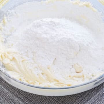 More powdered sugar added to mixture in glass bowl. 