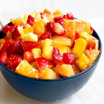 Easy Fruit Salad With Honey Lime Dressing in Blue Bowl on White Background.