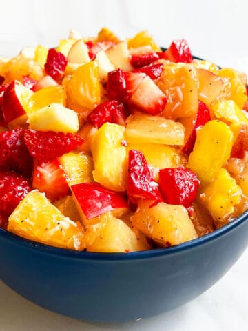 Easy Fruit Salad With Honey Lime Dressing in Blue Bowl on White Background.