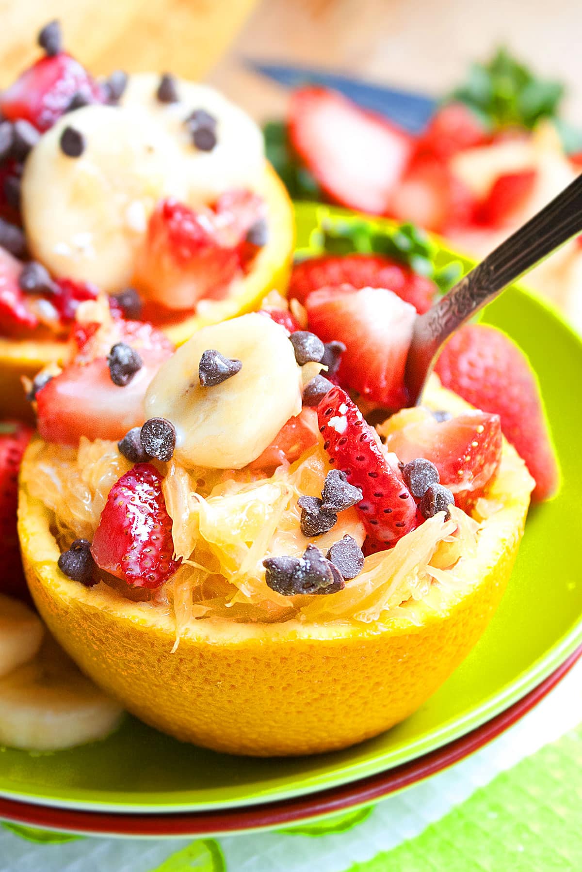 Orange fruit cup with spoon on green dish.
