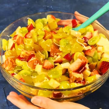 Mixed ingredients in glass bowl being moved from blue table to be chilled.