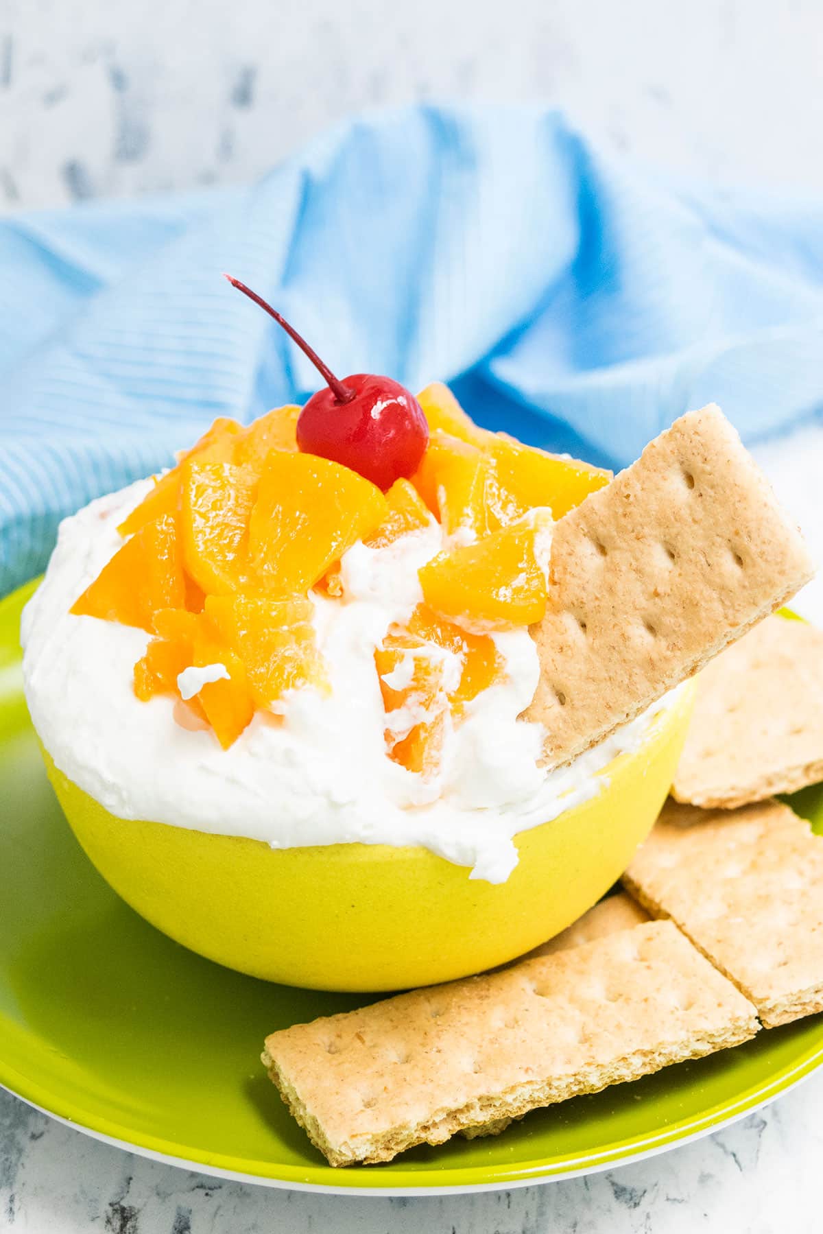 Peach Dip in Yellow Bowl With Graham Cracker Sticking Out to the Side. 