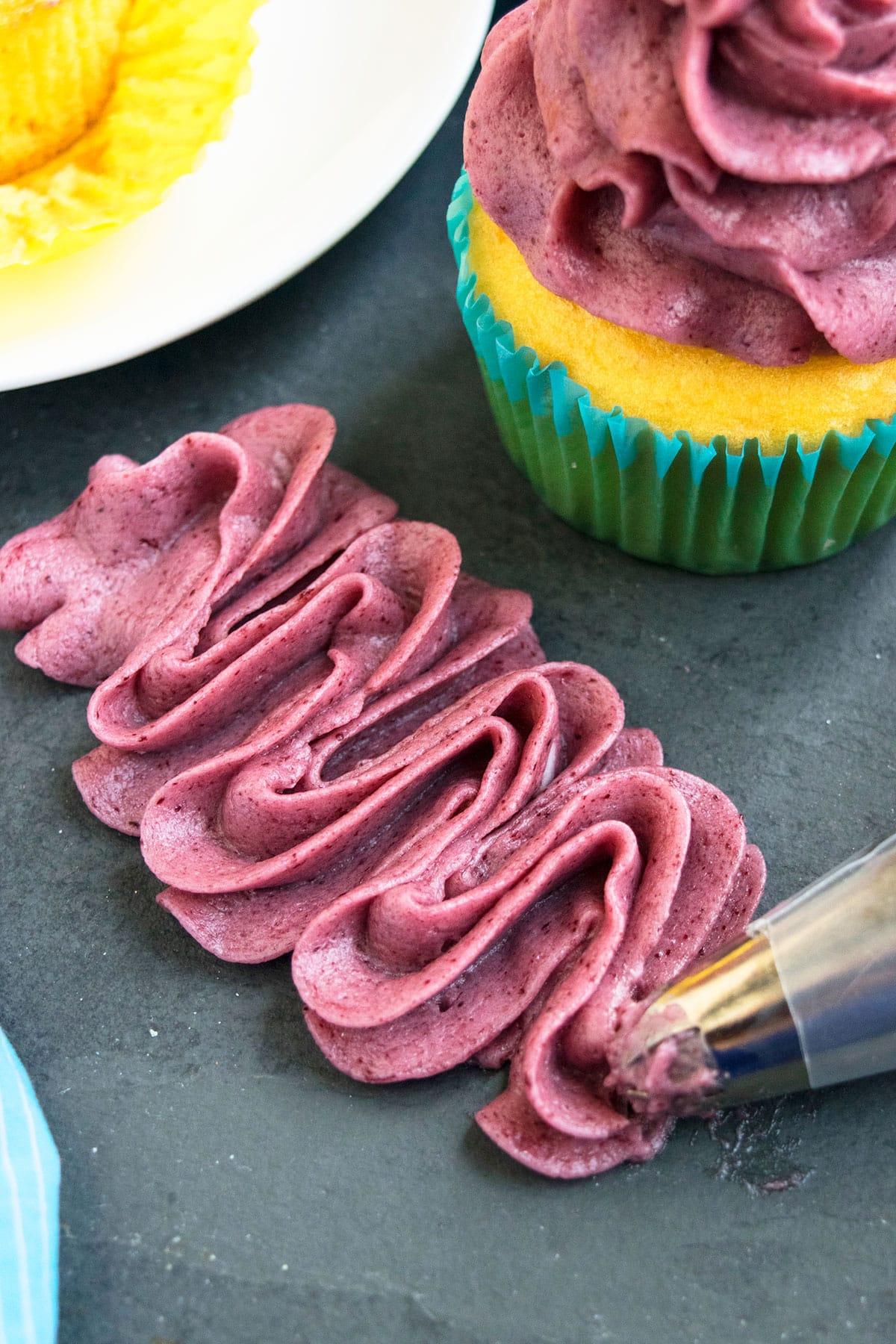 Fresh Blackberry icing piped on rustic gray dish with a piping bag. 
