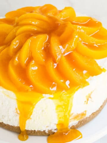 Easy No Bake Peach Cheesecake With Fresh or Canned Peaches and Graham Cracker Crust on White Cake Stand.