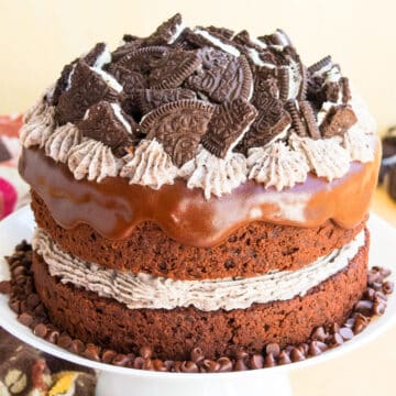Easy chocolate oreo cake (layer cake) with cookies and cream buttercream frosting and chocolate ganache on white cake stand.