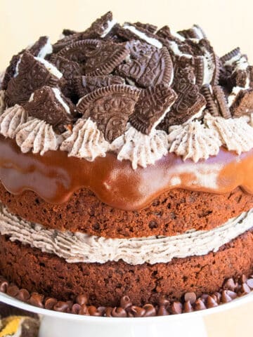 Easy chocolate oreo cake (layer cake) with cookies and cream buttercream frosting and chocolate ganache on white cake stand.