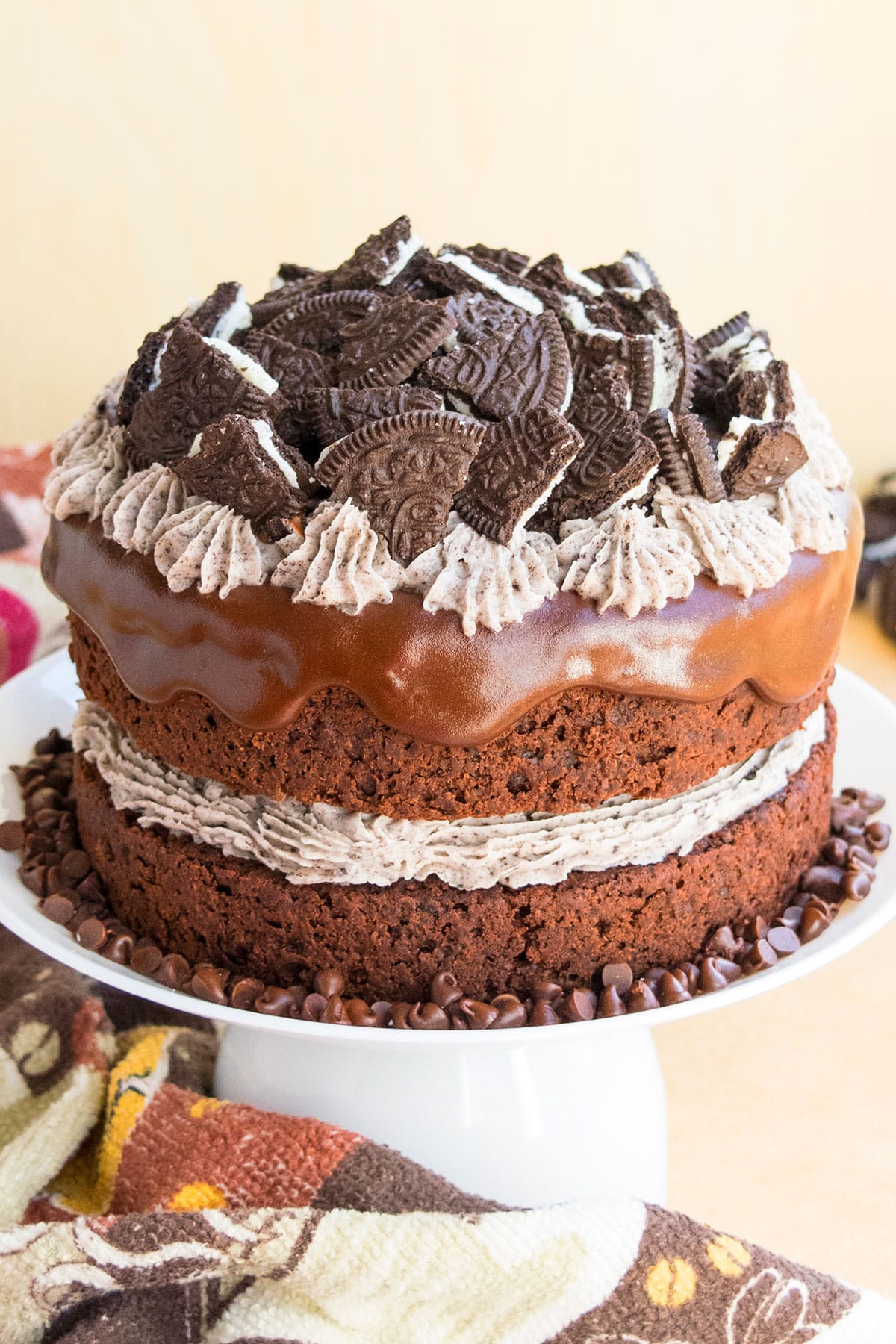 Easy chocolate oreo cake with oreo buttercream frosting and chocolate ganache on white cake stand. 