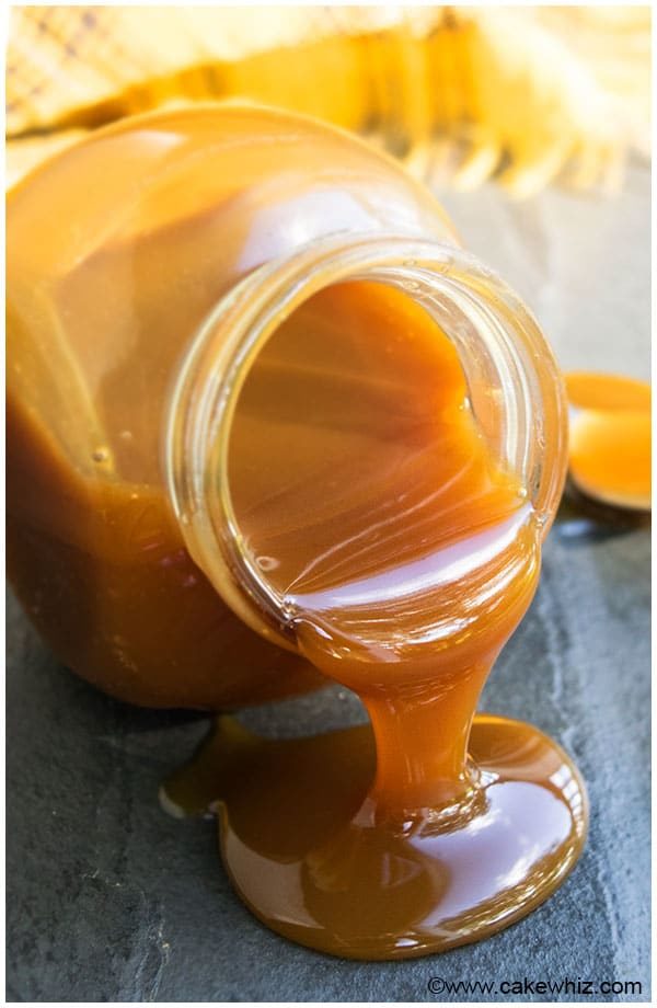 Best Caramel Drizzle for Cakes and Cupcakes Dripping out of Glass Jar on Gray Background