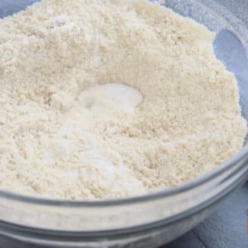 Milk added to crumbly mixture in glass bowl.