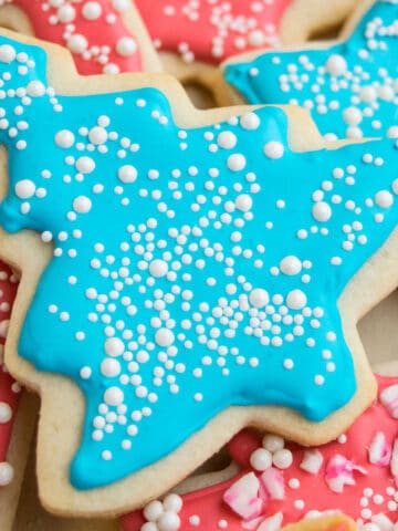 Easy Royal Icing With Meringue Powder Piped on Christmas Tree Cookie and Topped With White Sprinkles.