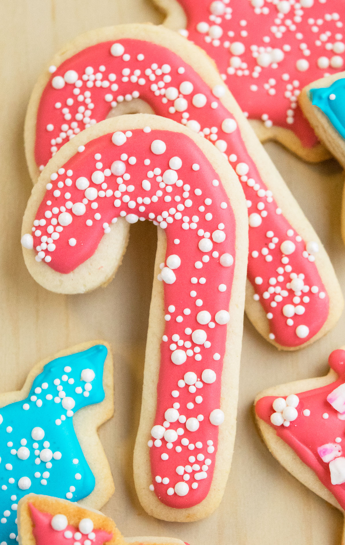 Cut out candy cane cookie decorated with icing that dries hard and white sprinkles. 