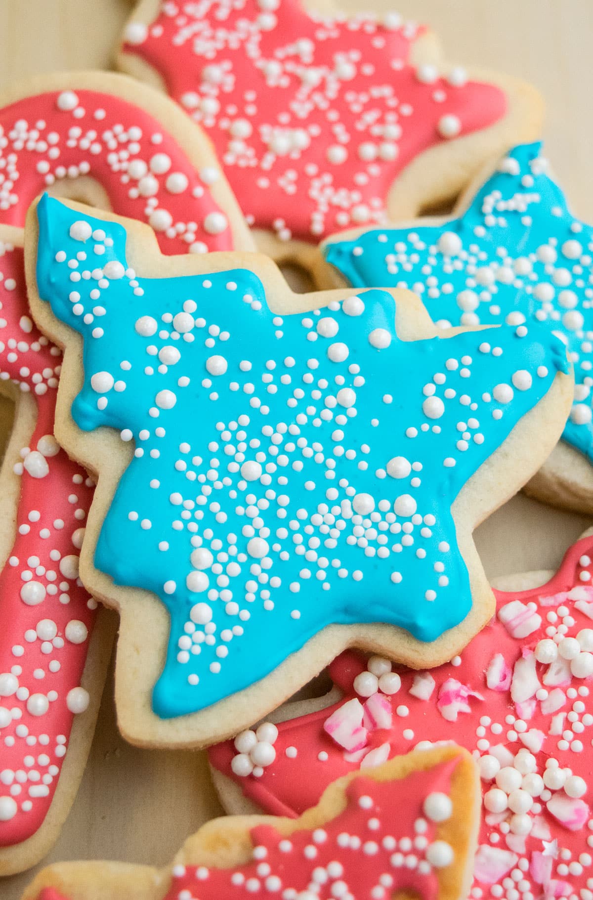Easy Royal Icing With Meringue Powder Decorated on Top of Christmas Tree Cookie and Topped With White Sprinkles. 