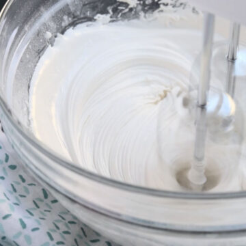 White cookie icing being mixed together until stiff peaks form. 