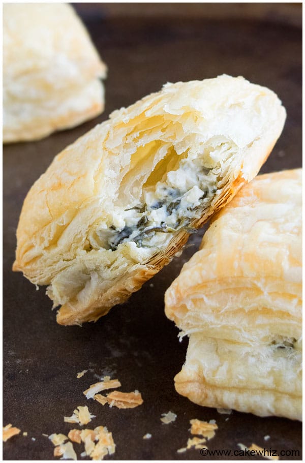 Partially Eaten Cheesy Spinach Puffs on Dark Metal Tray. 